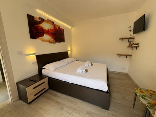 Camera da letto moderna dell'appartamento vittoriano a Campofilone con letto nero, illuminazione calda e arredo contemporaneo