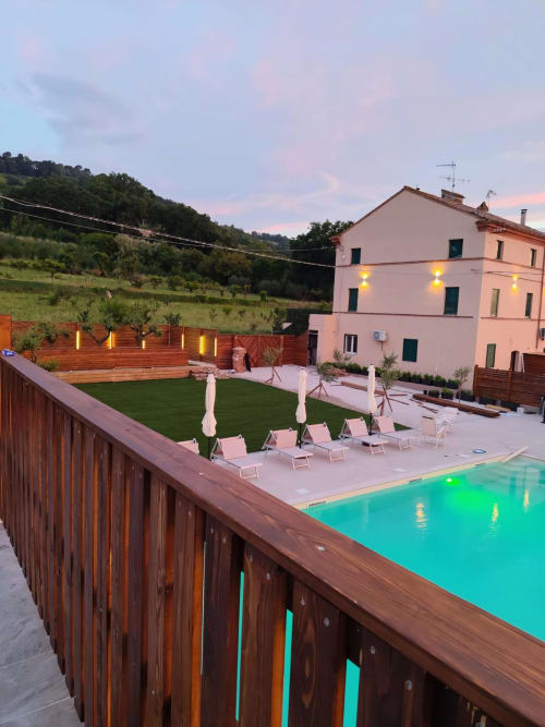 Appartamento Queen Hotel Victoria a Campofilone con piscina turchese, lettini e edificio rosa al tramonto