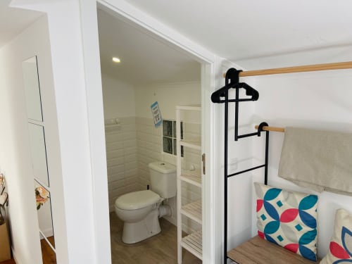 Banheiro e quarto modernos da Casa das 7 Janelas, Peniche com chuveiro, sanita e cama com almofadas coloridas