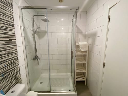 Banheiro moderno com azulejos brancos estilo metrô na Casa das 7 Janelas em Peniche, com portas de vidro e prateleira branca