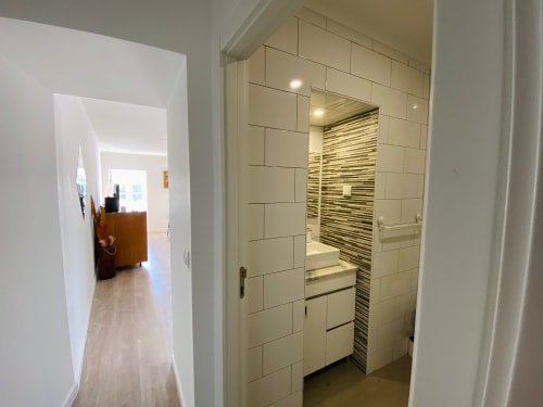 Banheiro moderno com azulejos brancos subway e parede de destaque com listras no apartamento Casa das 7 Janelas, Peniche