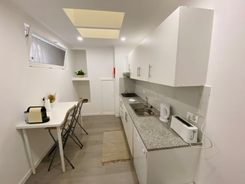 Cozinha e sala de jantar modernas e brancas no apartamento Casa das 7 Janelas, Peniche, com bancadas em granito e vista para a cidade
