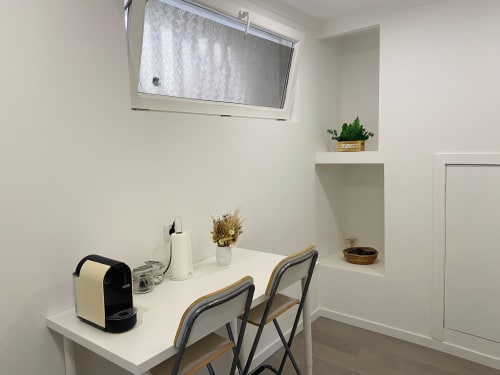 Espaço de trabalho luminoso em Casa das 7 Janelas em Peniche com secretária, cadeiras, máquina de café e plantas perto da janela