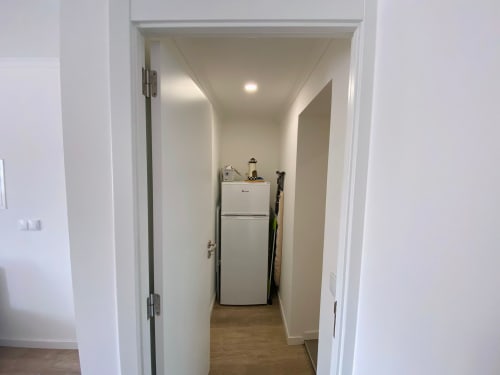 Corredor compacto da cozinha com geladeira branca no apartamento Casa das 7 Janelas em Peniche