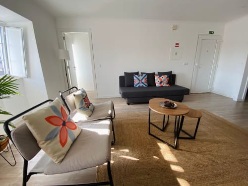 Sala de estar moderna do apartamento Casa das 7 Janelas em Peniche com sofá preto, mesa de madeira e vista para a cidade