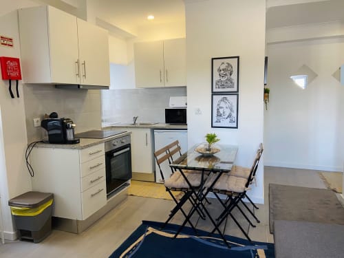 Cozinha e sala de jantar modernas no apartamento Casa das 7 Janelas, Peniche, com armários claros e vista para a cidade