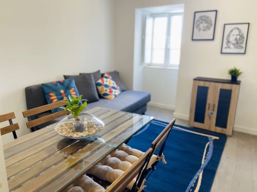 Sala de estar moderna da Casa das 7 Janelas, Peniche, com sofá, mesa de jantar, móveis em madeira e vista para a cidade