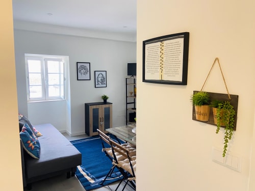 Quarto aconchegante na Casa das 7 Janelas em Peniche com tapete azul, cama, escrivaninha, plantas e quadros nas paredes