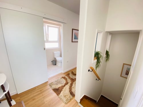 Corredor luminoso no apartamento Casa das 7 Janelas em Peniche com piso de madeira, paredes brancas e acesso ao banheiro