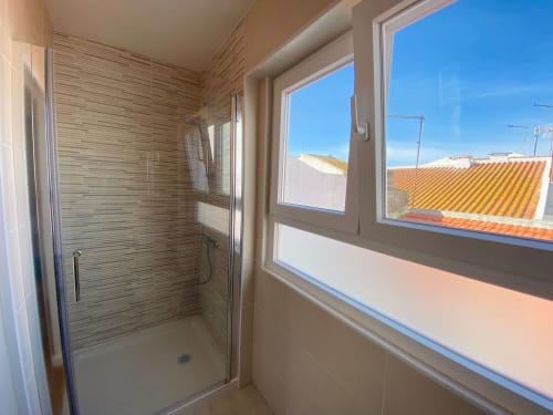 Banheiro moderno com azulejos listrados e vista para a cidade na casa de hóspedes Casa das 7 Janelas em Peniche, Portugal