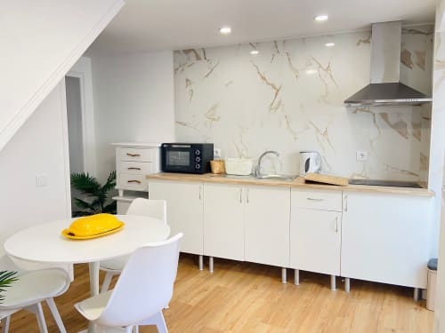 Cozinha e sala de refeições modernas no apartamento Casa das 7 Janelas, Peniche, com armários brancos e backsplash em mármore