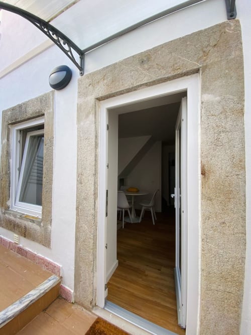 Porta aberta do apartamento na Casa das 7 Janelas em Peniche, mostrando sala de estar com mesa de jantar e elementos em madeira