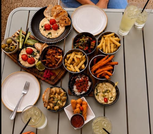 Overhead spread of appetizers and sides at The Old Kings Head, Kirton featuring flatbreads, fries, and beverages