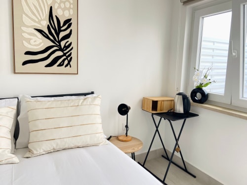 Quarto moderno da Casa das 7 Janelas em Peniche com decoração minimalista, secretária em madeira e luz natural
