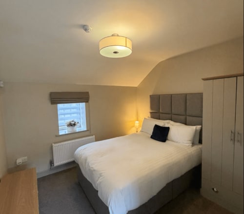 Modern bedroom at The Old Kings Head, Kirton, with double bed, grey headboard, white wardrobe and ceiling light