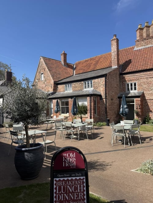 The Old Kings Head pub patio in Kirton with brick exterior, outdoor seating, and garden planters on a sunny day