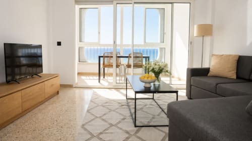 Apartamento moderno con vista al mar en Holidays Costa Brava, sofá gris, muebles de madera, balcón con vistas al Mediterráneo y