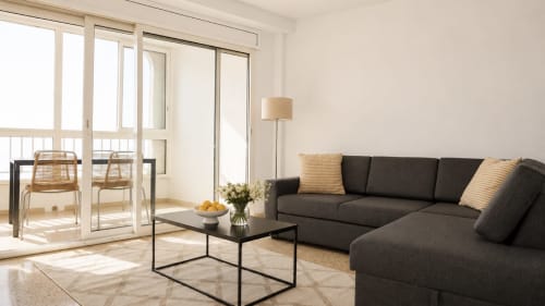 Salón moderno del apartamento Holidays Manhattan Sea View en Empuriabrava con sofá gris carbón, mesa de café negra y