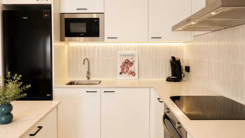 Cocina moderna blanca con electrodomésticos negros, azulejos tipo metro blancos y vista al mar en Holidays Manhattan, Empuriabrava