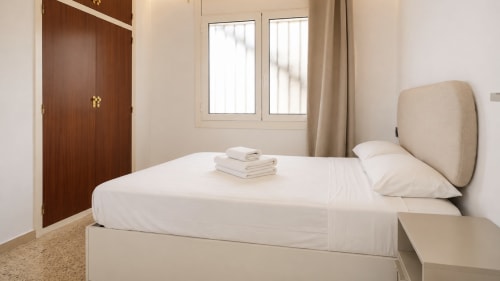 Dormitorio luminoso en Holidays Costa Brava con cama queen, vistas al mar, armario de madera y mobiliario moderno