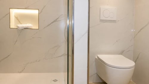 Baño moderno en Holidays Costa Brava, Empuriabrava con paredes de mármol, inodoro suspendido y nicho iluminado