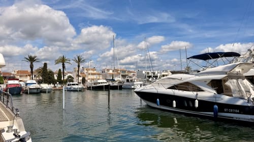 Vista del puerto de Empuriabrava con yates amarrados, veleros y arquitectura mediterránea bajo cielo azul