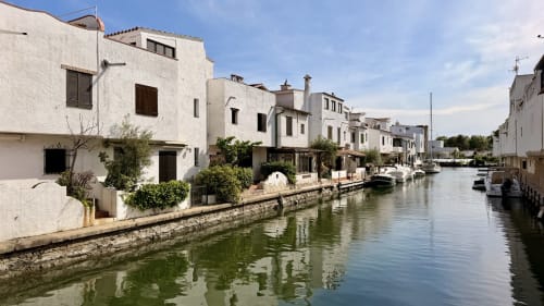 Apartamentos blancos frente al mar en Holidays Costa Brava, Empuriabrava, con barcos amarrados en el canal