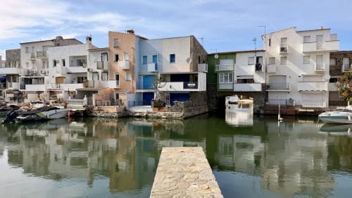 Apartamentos frente al mar en Empuriabrava con embarcaciones amarradas en aguas verdes tranquilas bajo cielo azul