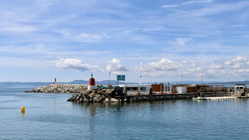 Marina de Empuriabrava con faro rojo y edificios portuarios, vistas del mar Mediterráneo desde Holidays Costa Brava