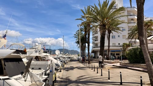 Marina con yates blancos, palmeras y apartamentos frente al mar en Empuriabrava, Costa Brava