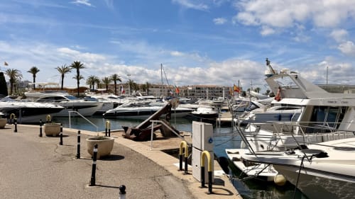 Marina de Empuriabrava con lujosos yates, palmeras y apartamentos junto al agua en Holidays Costa Brava