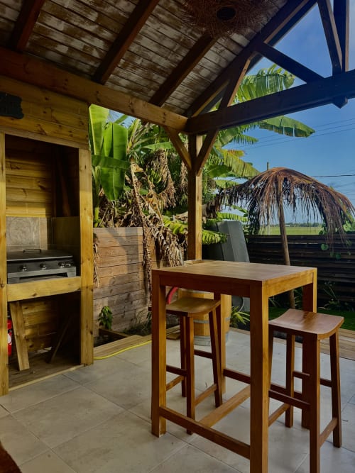 Espace repas extérieur de l'appartement Bielle, Tiki Kaz, Saint François avec pergola en bois, bar table et vue tropicale