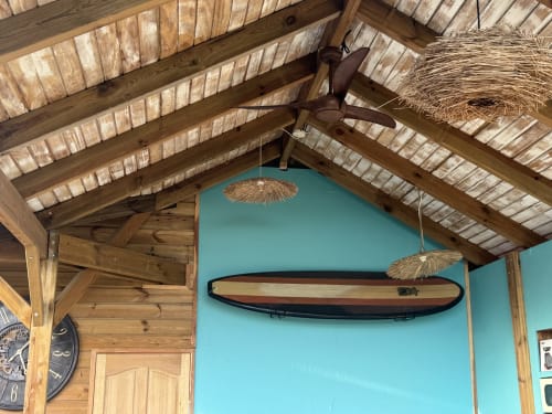 L'appartement Bielle de Tiki Kaz offre des poutres apparentes, une décoration murale de surf et des ventilateurs de plafond tropicaux turquoise