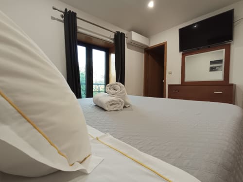 Quarto espaçoso na Quinta d'Areda com camas individuais, toalhas enroladas, vista para o lago, TV de tela plana, cortinas escuras e madeira