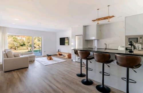Cozinha integrada moderna e sala de estar na Casa Carvalho, Serração House Gerês, com vista para o rio e iluminação em madeira