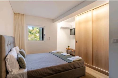 Quarto moderno na Casa Serração Gerês com vista para rio, guarda-roupa de madeira, cama com almofadas, janela com vista para paisagem verde e