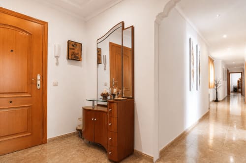Pasillo del apartamento Riurau Home Quintanes en Calp con puerta de madera, espejo de pared y piso de baldosas