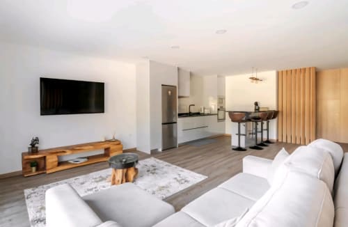 Sala de estar integrada moderna na Casa Serração com sofá branco, TV na parede, móveis em madeira e cozinha no Rio