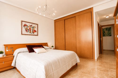 Dormitorio moderno en Riurau Home de Calp con muebles de madera, ropa de cama blanca y armarios empotrados