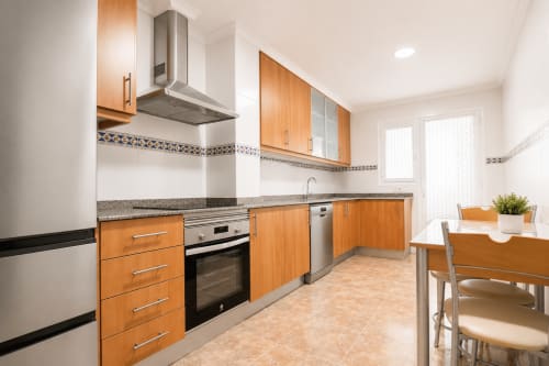 Cocina moderna con muebles de madera, electrodomésticos de acero inoxidable y zona de comedor en apartamento Riurau Home Quintanes, Calp