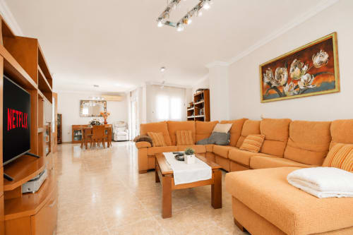 Amplio salón en Riurau Home de Calp con sofá seccional naranja, televisor, comedor y equipamiento moderno