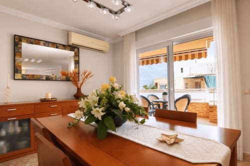 Comedor del apartamento Riurau Home Quintanes en Calp: mesa de madera, flores, vistas al mar y mobiliario moderno