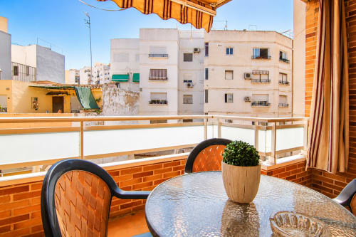Vista del balcón del apartamento Riurau Home en Calp con mesa de comedor, planta en maceta y arquitectura mediterránea costera