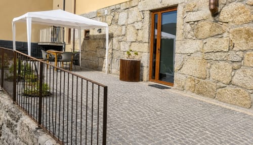 Pátio da Casinha Serração em Gerês com muros de pedra, toldo branco, área de estar e floreiras de madeira em Rio Caldo