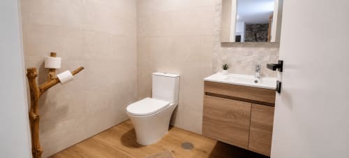 Banheiro moderno da Pousada Serração Gerês com espelho suspenso, vaso sanitário e toalheiro decorativo em galho