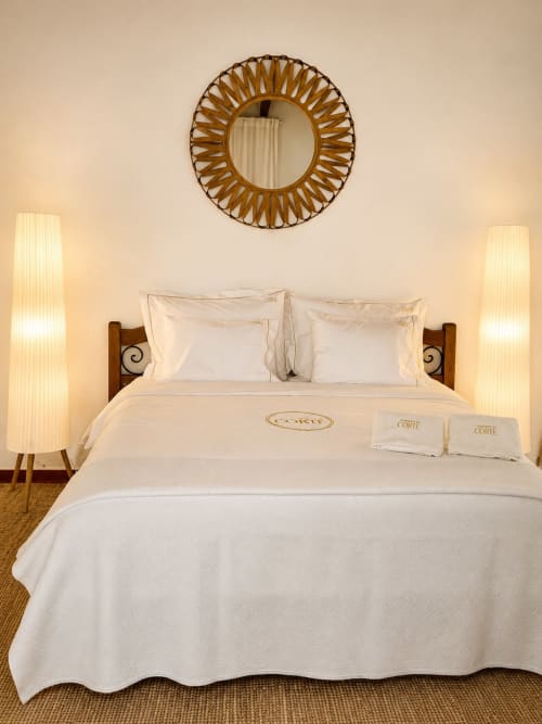 Quarto de luxo na Herdade da Côrte com roupa de cama creme, espelho sol e iluminação ambiente em Tavira, Portugal
