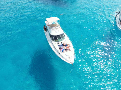 Motoscafo bianco ancorato nelle acque turchesi di Lampedusa con ospiti che si rilassano in coperta