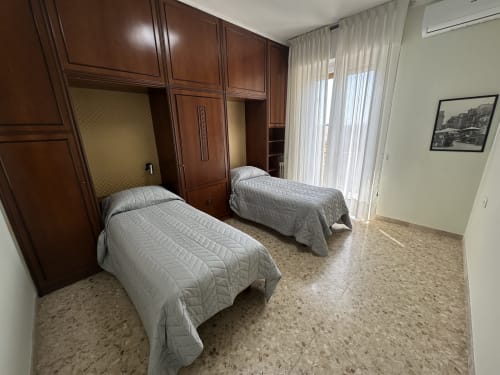 Camera doppia con armadio in legno, coperte grigie e accesso al balcone presso 10 Minutes B&B a Verona