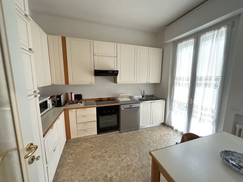 Cucina moderna nella B&B di Verona con armadietti color crema, elettrodomestici in acciaio inox e porte francesi verso il balcone