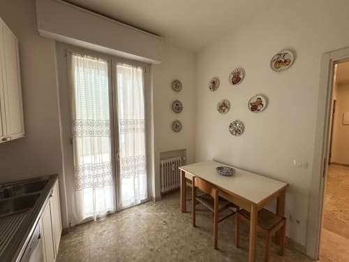 Luminosa zona pranzo nell'Apartment Skyview del 10 Minutes B&B Verona, con tavolo in legno, piatti decorativi e porte finestre sul balcone